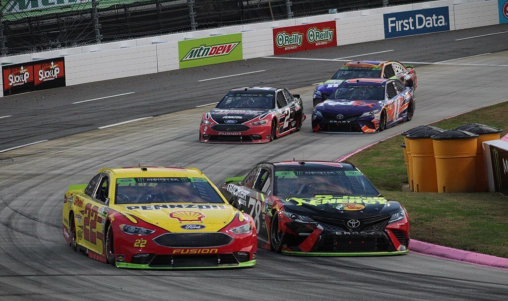 Five Nascar race cars turning a corner