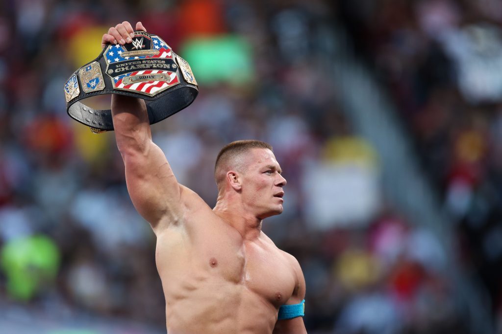 Jon Cena holding up a title belt at a WWE show