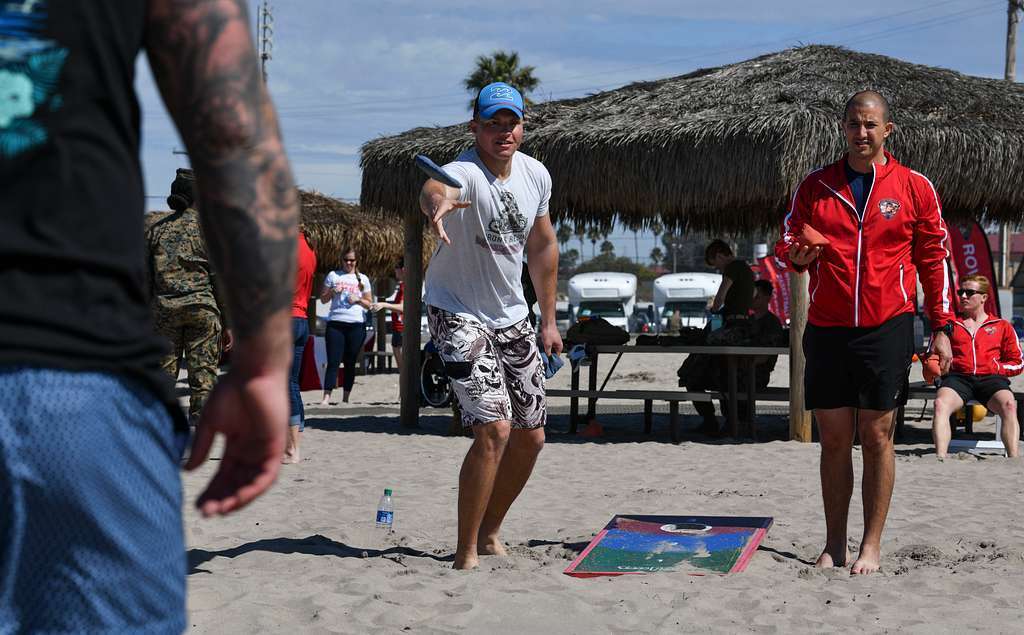 Two people playing cornhole on the beach